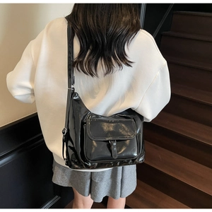 Détail de la bandoulière réglable et texture brillante du sac demi-lune noir