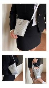 Close-up of silver woven texture mini bucket bag with metallic twist lock and chain strap