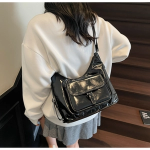 Détail du sac cabas en cuir verni noir brillant avec poche avant à rabat fonctionnelle