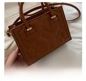 Close-up of brown embossed floral pattern and gold metal hardware on the shoulder bag