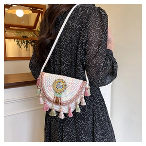 Rear view of a model wearing the white woven crossbody bag with colorful tassels and beads