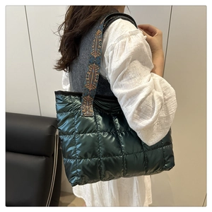 Detail of quilted puffy tote bag with metallic finish and ethnic style wide shoulder strap