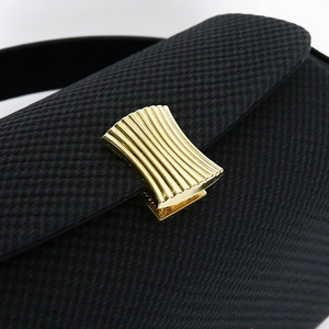 Detail of black textured leather handbag with elegant gold fan-shaped metal buckle