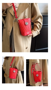 Detail of red woven bucket bag with metallic round buckle and adjustable strap