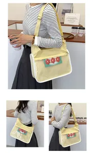 Detail of light yellow canvas messenger bag featuring a clear PVC window with red floral icons