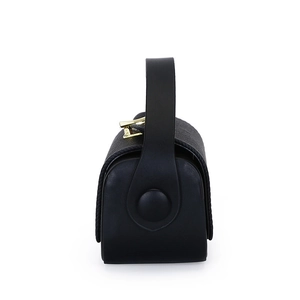 Side view of black leather box bag with textured finish and gold metal clasp detail
