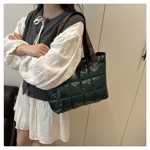 Detail view of dark green quilted tote bag with ethnic jacquard strap on female model