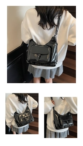 Détail du sac à bandoulière en cuir verni noir brillant montrant le fini miroir et la poche