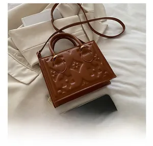 Detailed view of the embossed leather texture and pattern on a brown crossbody handbag