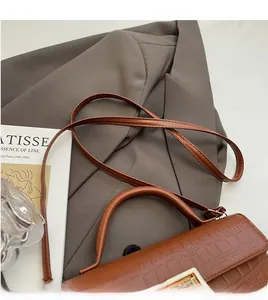 Detail of brown stone-textured handbag with gold buckle and top handle in a lifestyle setting