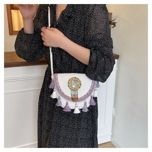 Detail of bohemian straw crossbody bag with colorful beadwork and purple tassels