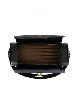 Detail view of the spacious inner compartment and gold lock on this black cylinder bag