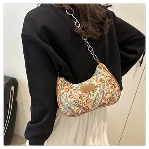 Détail du sac bandoulière floral avec bandoulière en chaîne et logo en cuir