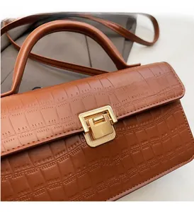 Close-up of brown crocodile texture leather and polished gold metal lock on the handbag