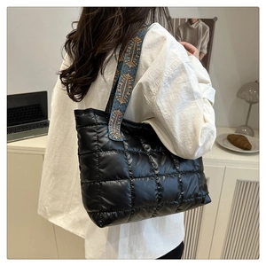 Close-up of black quilted tote bag with intricate blue and gold jacquard woven strap