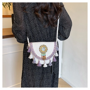 Detail of bohemian woven crossbody bag featuring ethnic beadwork and purple tassels