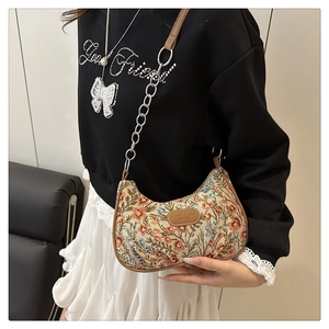 Détail du tissu de tapisserie floral et des finitions en cuir brun sur le sac lune