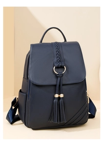 Close-up of navy blue textured leather backpack featuring double tassels and gold hardware