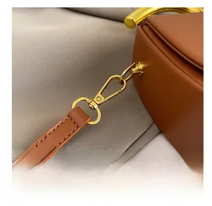 Details der Premium-Ledernähte und glänzender Goldmetallhaken an der braunen Satteltasche