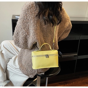 Vista dettagliata della borsa a scatola gialla in pelle martellata con zip argentata