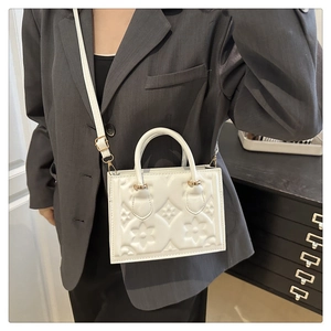 Detail of white square crossbody bag with embossed floral texture and gold hardware