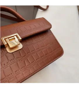 Detail of brown crocodile texture leather bag with elegant golden square metal clasp