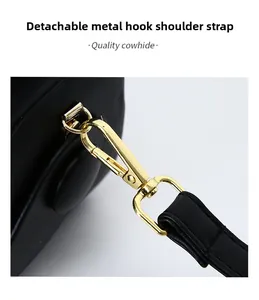 Detail of golden hardware hook and detachable shoulder strap on premium black leather bag
