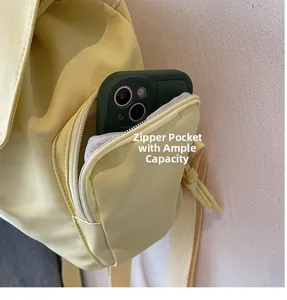 Detailaufnahme der Reißverschlusstasche am hellgelben Rucksack mit einem Smartphone