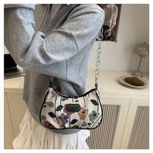 Détail de la texture jacquard florale avec bandoulière chaîne argentée sur le sac