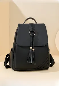 Detail of black pebbled leather backpack with tassels and golden metal ring hardware