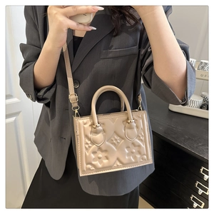 Close-up of beige embossed handbag with floral textures and pale gold metal hardware