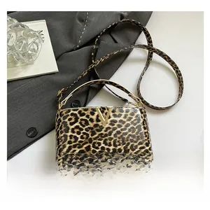 Detail of leopard print crossbody bag with gold V-buckle and glossy patent finish