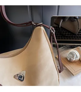 Detail of beige nylon tote bag with polished metal plate and brown adjustable strap