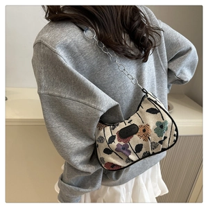 Détail du sac croissant en jacquard floral avec chaîne argentée et patch logo en cuir