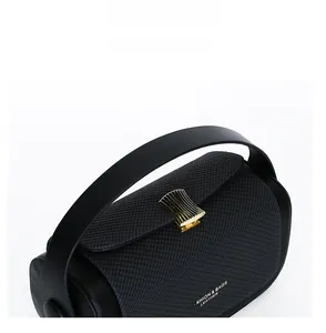 Detail of cross-textured black leather bag featuring a gold fan-shaped metal buckle