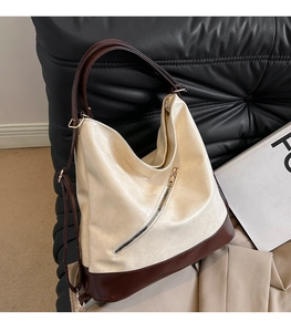 Detail of multi-functional cream and brown leather bag with diagonal zipper on sofa