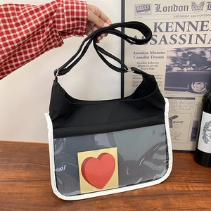 Black canvas messenger bag with a large transparent window and heart detail in a lifestyle setting