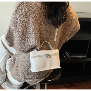Detailed view of a white lychee grain leather mini box bag worn by a model in a cozy setting