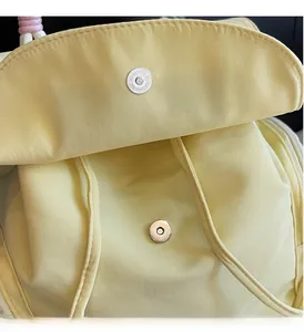 Detail des silbernen Magnetverschlusses an einem hellgelben Nylon-Pendler-Rucksack