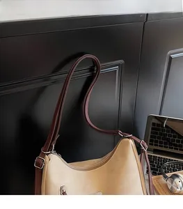 Detail of minimalist beige hobo bag showing adjustable shoulder strap and leather texture