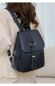 Detail of dark blue faux leather backpack with tassels and gold ring on the back of a model