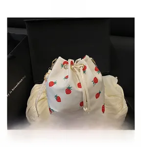 White drawstring bucket bag with strawberry print and gold hardware in elegant gift box
