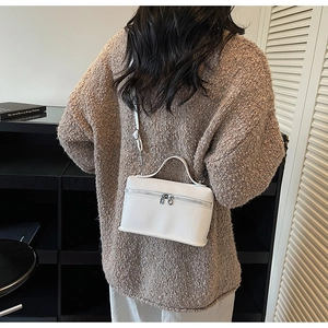 Vue arrière du sac carré en cuir blanc porté avec un pull décontracté et une bandoulière