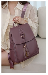 Detail of burgundy PU leather backpack with tassel ornament and golden ring accent