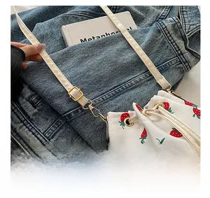 Detail of adjustable strap with gold buckle on strawberry printed canvas bucket bag
