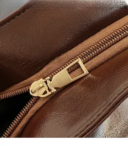Detail of smooth gold metal zipper and premium brown leather texture on handbag