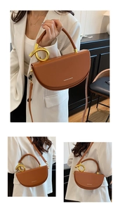 Detail einer braunen Satteltasche mit goldenem Knotengriff und verstellbarem Riemen