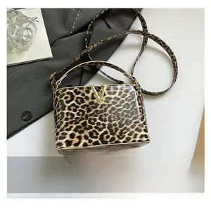 Detail of the leopard print crossbody bag featuring a gold V-logo buckle and leather strap