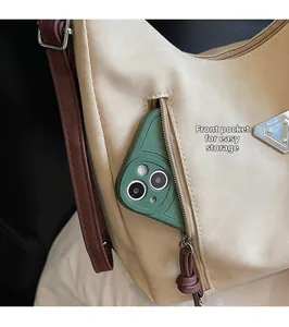 Detail of front zipper pocket on beige tote showing convenient phone storage and metallic tag