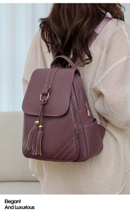 Detail showing the elegant fringed pendant and woven texture on a purple-pink PU backpack
